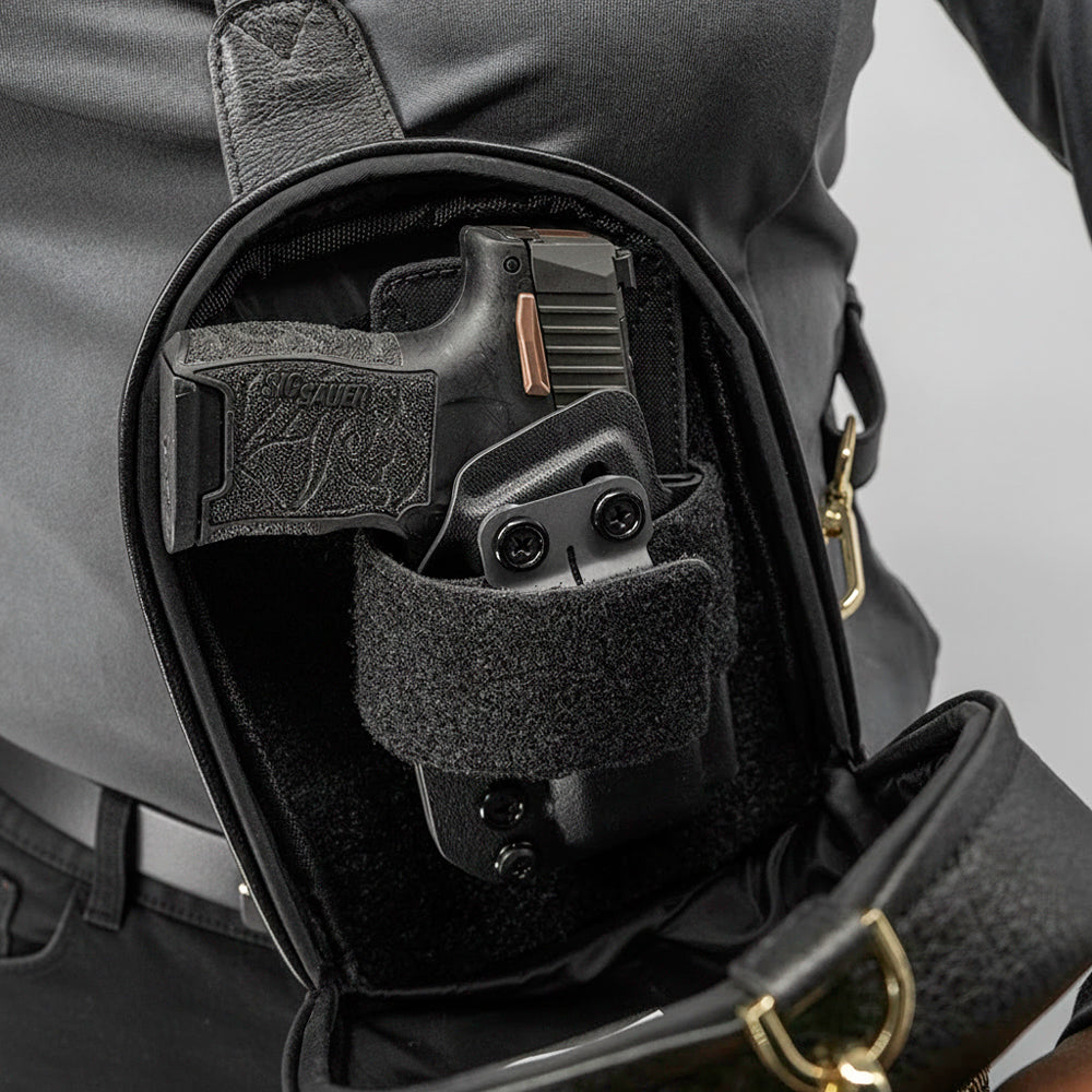Black gun holster attached to a black leather bag on a gray background