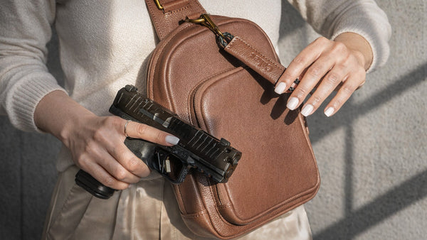 Woman holding a handgun beside a brown leather concealed carry crossbody bag, women's concealed carry trends