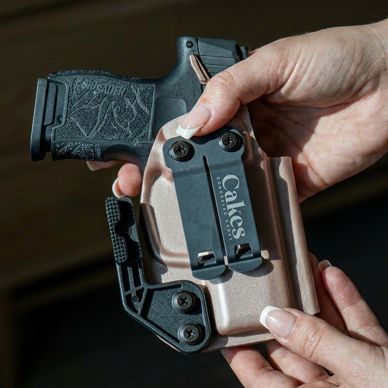 Close-up of hands holding a black handgun secured in a Metalic Kydex holster with a black belt clip for Convertible bag use