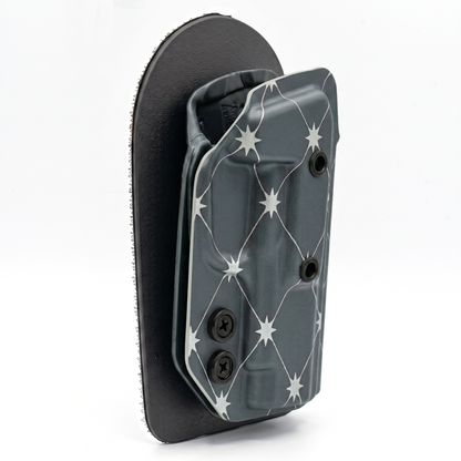 CAKES CONCEALED SILVER PREMIUM HOLSTER ON A BLACK VELCRO BACKER ANGLED.